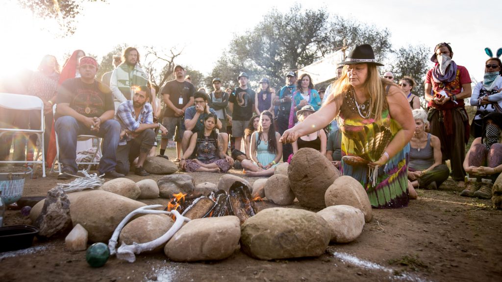 Woman tending to fire with observers and participants