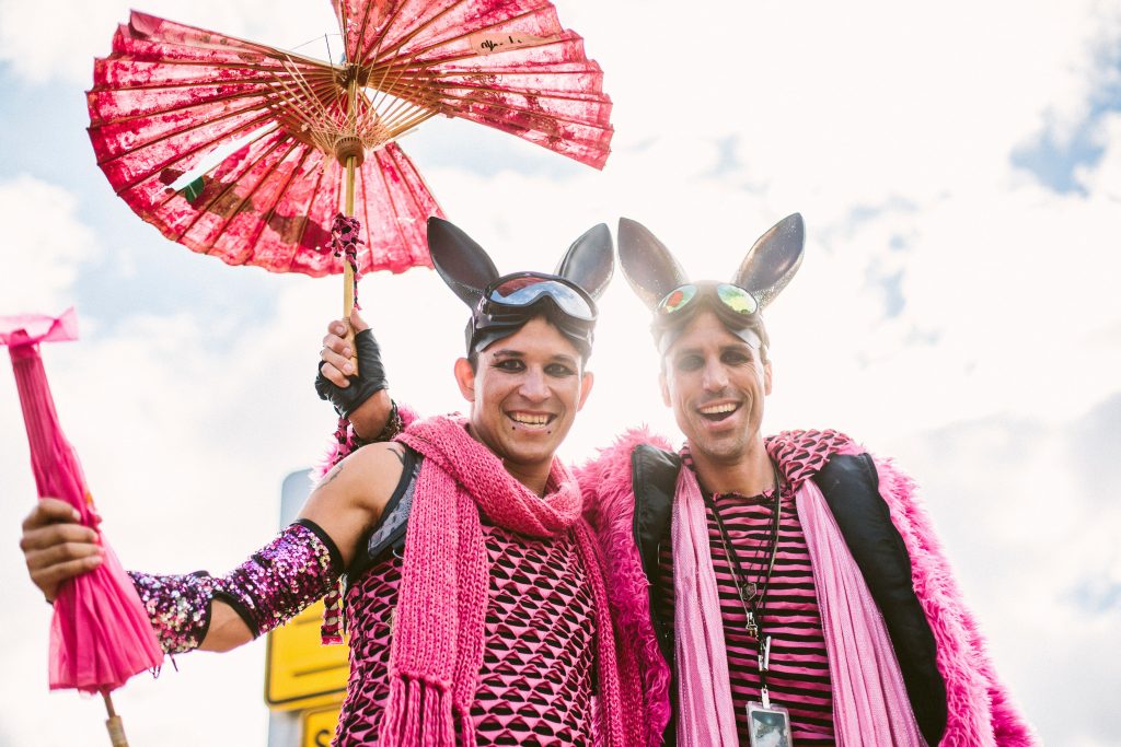 Two light skinned males dressed in pink festival attire